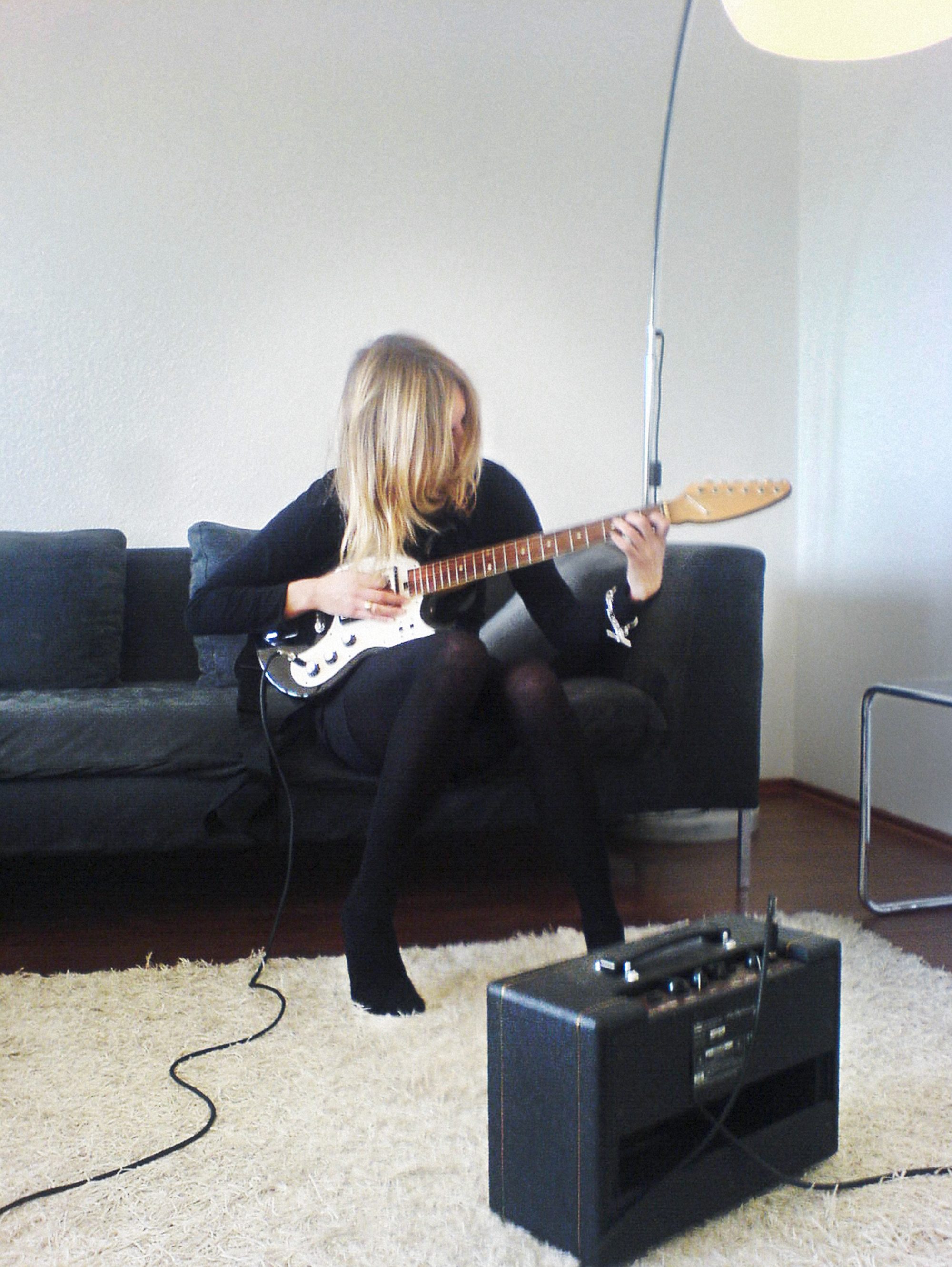 frau-spielt-e-gitarre-mit-verstaerker-auf-sofa-sexy