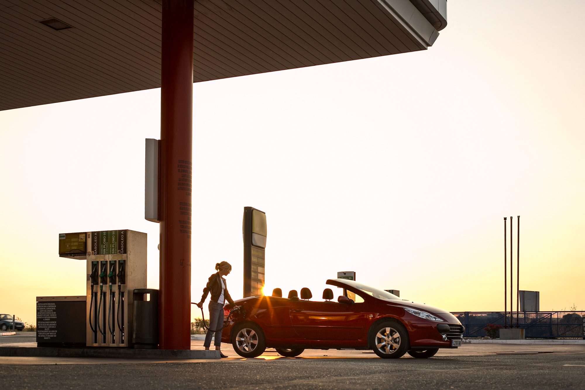 frau-tankt-kabrio-auto-an-tankstelle-gegenlicht