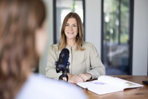 Mitarbeiterin mit Microfon im Interview. Moderne Unternehmenskommunikation umfasst auch Social Media
