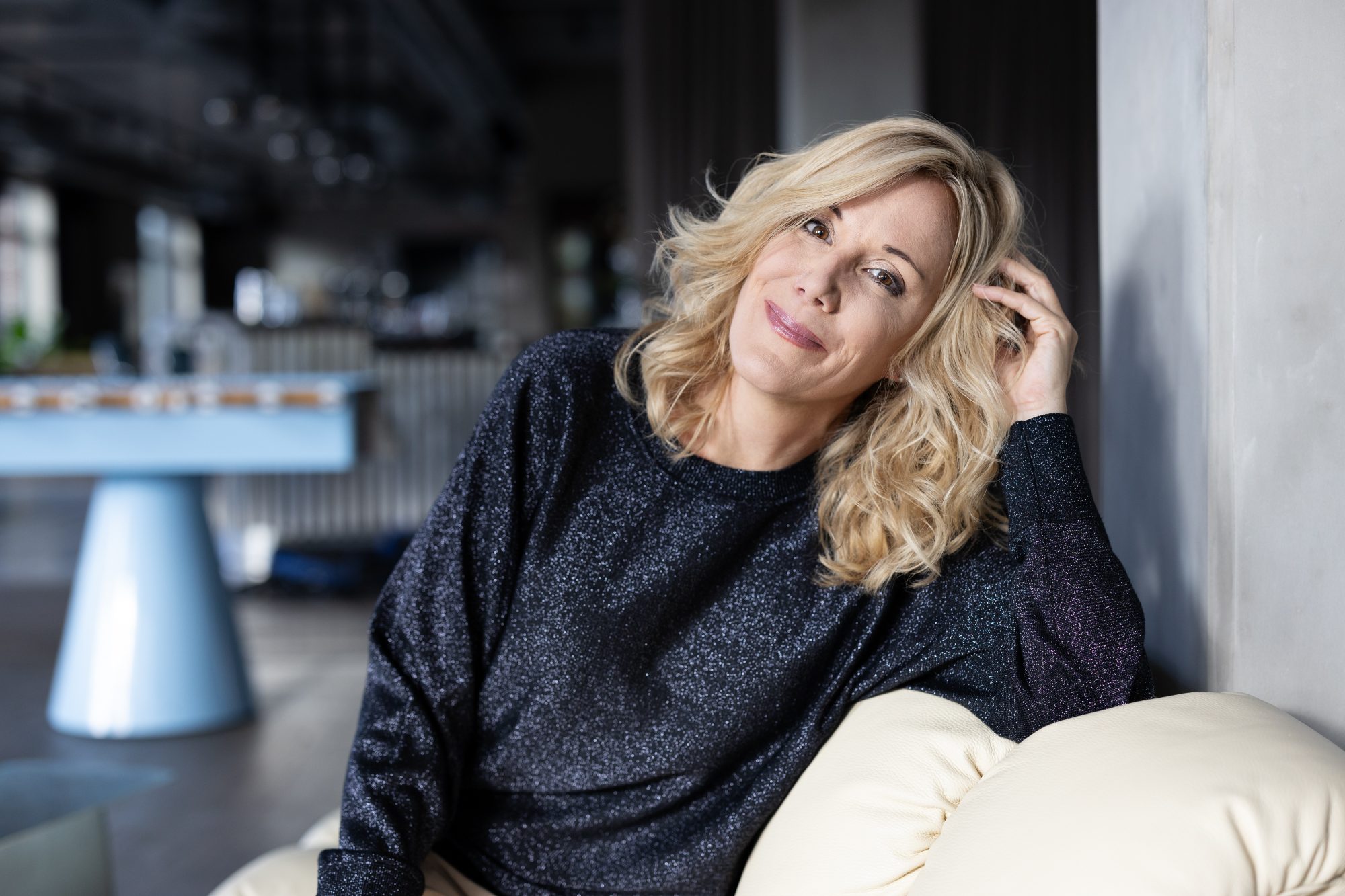Tanja Lipinski mit leicht geneigtem Kopf und einer Hand im Haar.