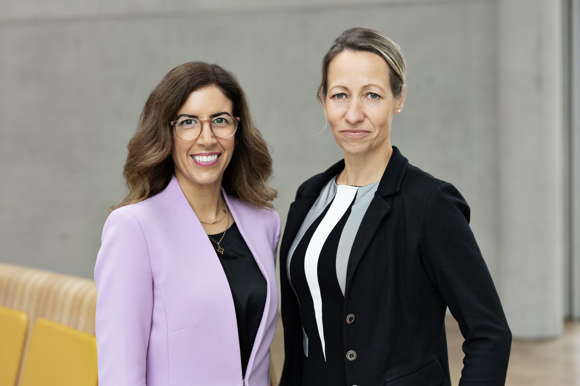 Zwei Frauen von Bündnis Technik stehen nebeneinander vor einer hellen Wand.