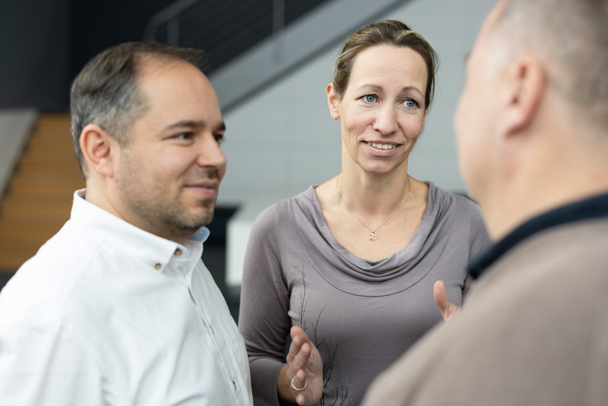 Zwei Mitglieder von Bündnis Technik sprechen mit einem im Vordergrund angeschnittenen Kollegen.