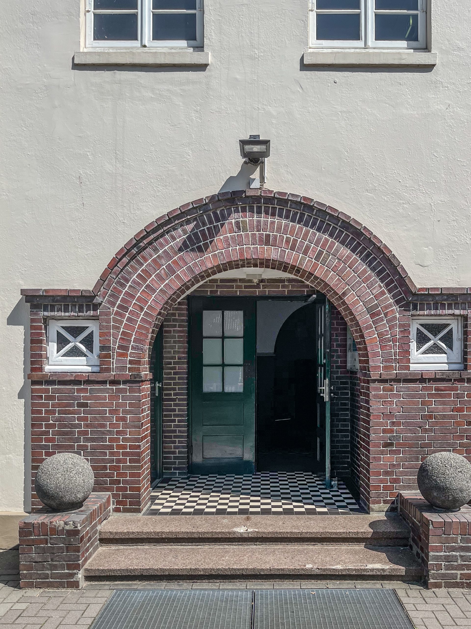 Eingang der Schule mit gemauertem Rundbogen und grüner Tür.