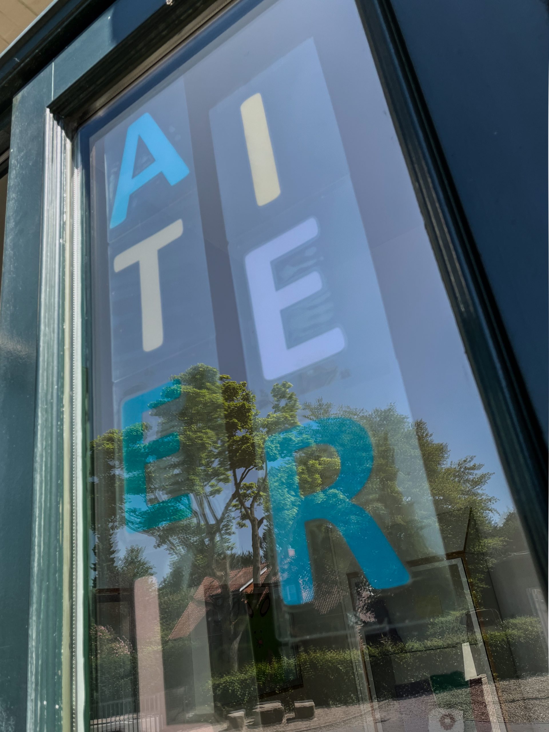 Bunte Buchstaben bilden das Wort Atelier auf einer Glastür.