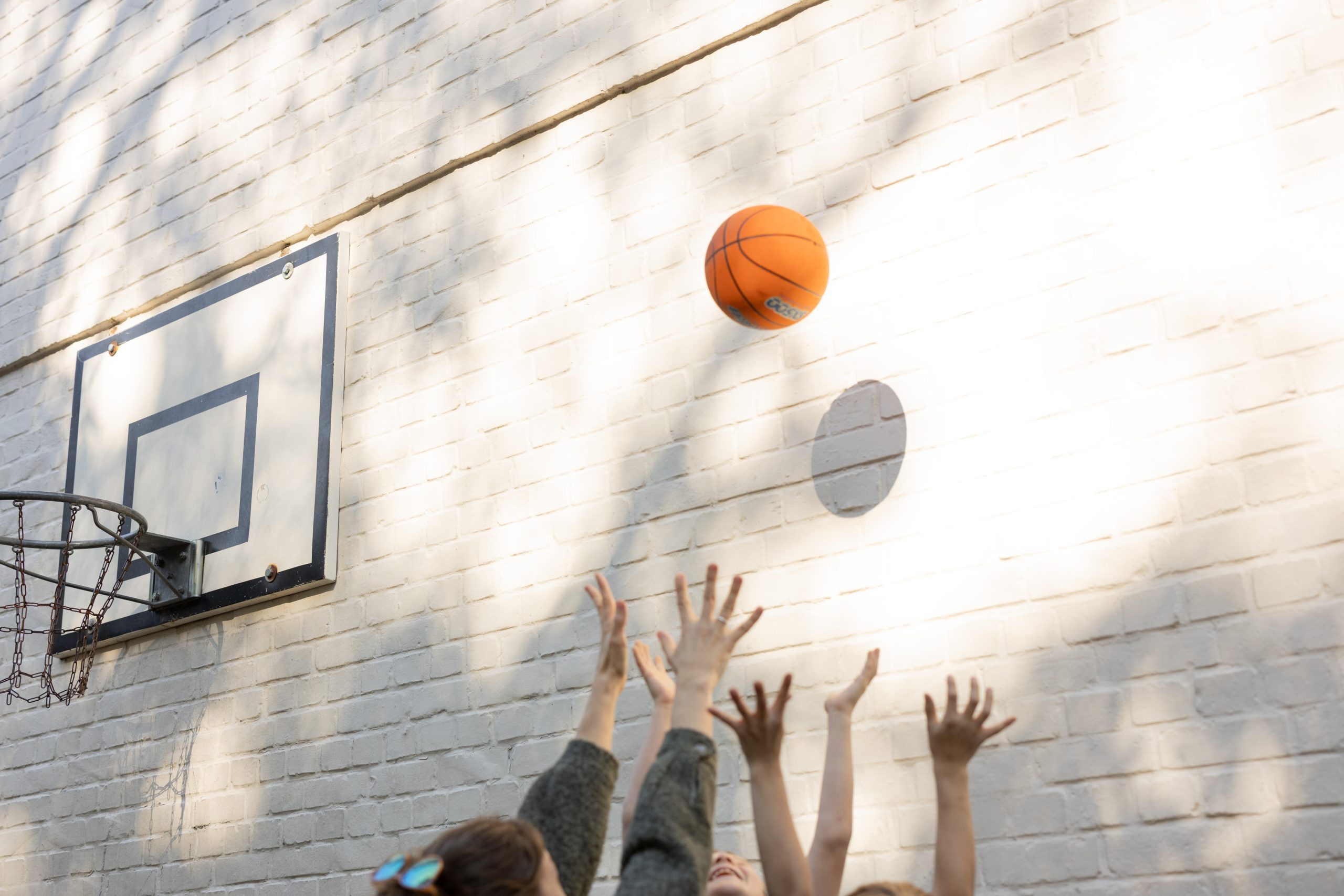 Basketball und ausgestreckte Hände vor einer hellen Wand – Schule Schulkamp.